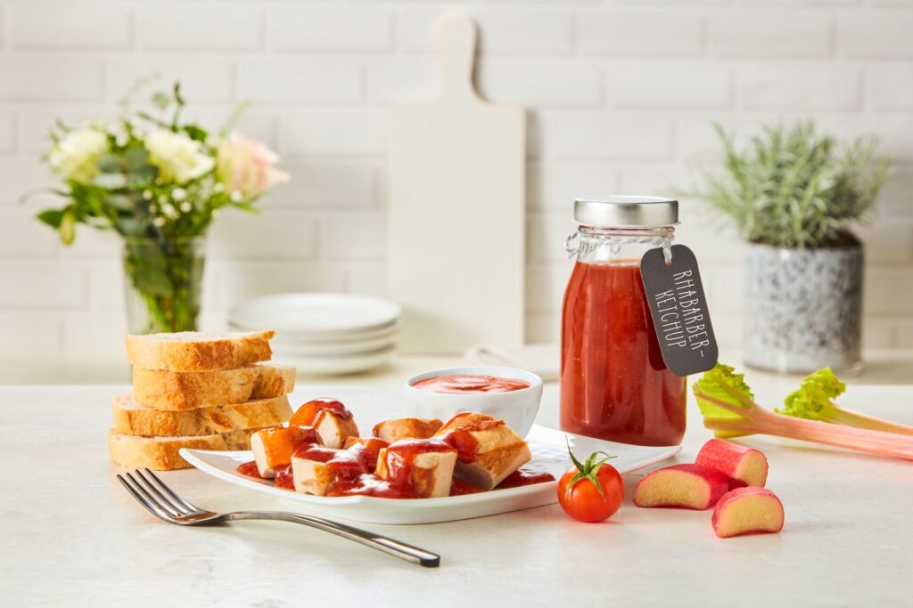Glasflaschen mit selbstgemachtem Rhabarber-Ketchup auf einem Tisch.