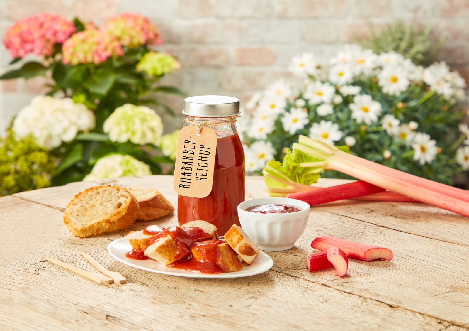 Rhabarber-Ketchup-Flaschen stehen im Garten auf einem Holztisch.
